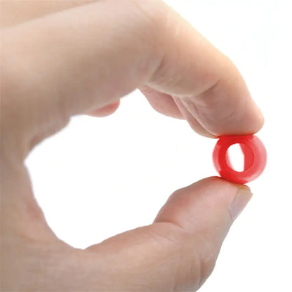 Hand holding a small red ring against a white background