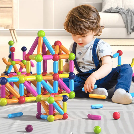 Child playing with colorful magnetic building blocks on a light-colored floor.