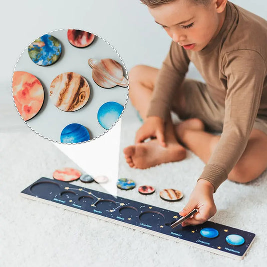 Child playing with solar system model on a light gray surface